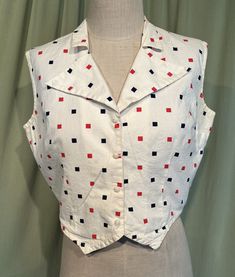 This is a cute vintages blouse from the 50s or early 60s. Label is washed out, no size tags. The bust measures 40" with measurements below. Made of cotton with a small grid weave accented with printed red & blue squares. It is sleeveless & has 4 buttons down the front. The hemline is front is pointed on each side, weskit style. The collar is a wide flared butterfly style collar. Cropped style blouse.  The top is in very good condition! No damage. Slightly yellowed under the arms. No other stains or soil. Super cute!  If you have never worn vintage before, please measure yourself!! Vintage sizes run smaller than today's sizes, know your measurements before buying! Bust measured from side seam to side seam at the underarm: 20.5" for a 40" or smaller bust Hemline from side seam to side seam:1 Vintage Fitted Vest For Summer, Retro Fitted Summer Vest, Retro Fitted Vest For Summer, Retro Cotton Vest With Buttons, Vintage Red Sleeveless Top, Retro Red Sleeveless Vest, Red Sleeveless Retro Vest, Vintage Vest Tops For Summer, Red Cotton Retro Vest