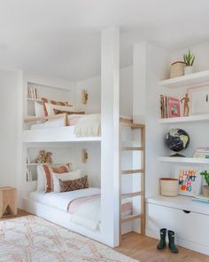 a white bedroom with bunk beds and shelves filled with books on top of each bed