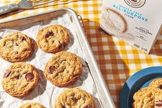 chocolate chip cookies on a baking sheet next to a carton of milk and utensils