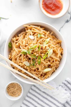 a bowl filled with noodles and chopsticks on top of a white countertop