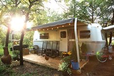 an rv is parked in the woods with its awning open and it's sun shining