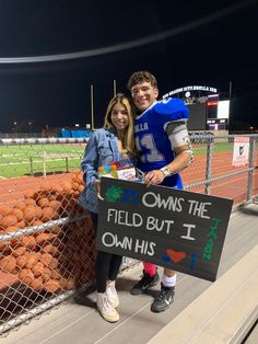 a man and woman standing next to each other holding a sign that says, i own the field but i own his