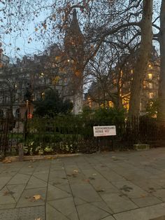 a sign is posted on the fence in front of some trees with leaves around it