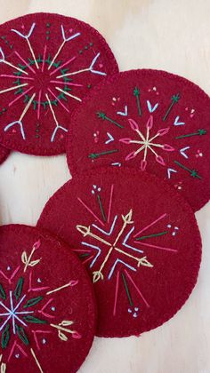 four red coasters with snowflakes on them sitting on top of a table