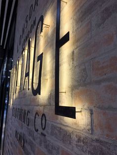 an illuminated sign on the side of a brick building that reads,'coming to town '