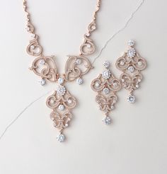 a necklace and earring set on a white surface, with diamonds in the center