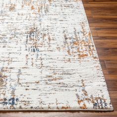 a white rug with an orange and blue design on top of wooden flooring in a room