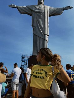 a woman is standing in front of the statue of christ with her hands on her hips