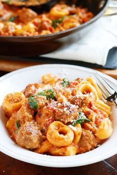 a plate of pasta with meat sauce and parmesan cheese on the side next to a skillet