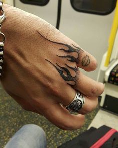 a person with a ring on their finger and some tattoos on his hand is shown