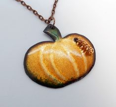 a necklace with an apple shaped pendant hanging from it's side on a chain