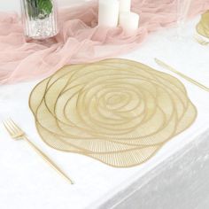 a table topped with plates and candles next to a vase filled with flowers on top of a white table cloth