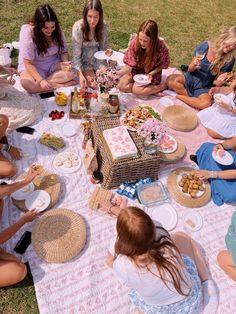 a group of women sitting on top of a grass covered field next to each other