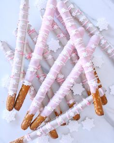 some pretzels with pink and white frosting on them sitting next to snowflakes