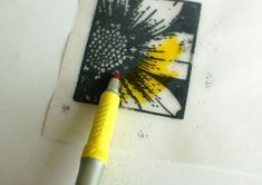 a yellow and black flower is on top of a piece of paper with a marker