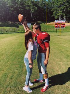 a man and woman standing on top of a lush green field next to each other