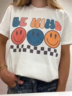 Look super cute and spread good vibes in this trendy retro Smiley Face Be Kind T Shirt!  Spread good vibes in this super soft comfort colors t shirt, and look great doing it! Please note: This item is PRINTED, not embroidered. Printed on a soft, 100% cotton comfort colors t shirt.  SIZING: Our T Shirts are unisex sizing.  We suggest ordering your normal size for a regular fit.  If you want an oversized fit we suggest ordering a size up. Please contact us directly for any custom/bulk orders! T Shirts Trendy, T Shirt Inspiration Design, Groovy T Shirt Designs, 90s Shirt Design, Trendy Multicolor T-shirt With Text Print, Retro White T-shirt With Funny Print, White Retro Print T-shirt For Streetwear, Trendy Cotton T-shirt With Retro Print, Groovy Shirt Designs