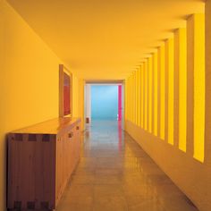 an empty hallway leading to the ocean with bright yellow walls and columns on either side