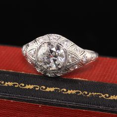 an antique diamond ring sitting on top of a red velvet book with gold trimming