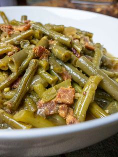 a white bowl filled with green beans and bacon