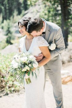 a bride and groom embracing each other in the woods