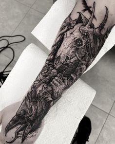 a man's arm with a black and white tattoo design on the left forearm