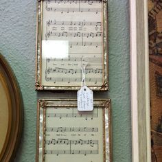 two framed music sheets are hung on the wall next to a mirror with a price tag