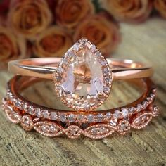 three rose gold wedding rings with an oval cut diamond in the center, and a pear shaped morganite on each band