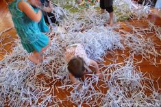 two children playing with shredded paper on the floor