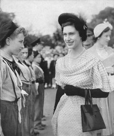 an old black and white photo of two women standing next to each other with people in the background