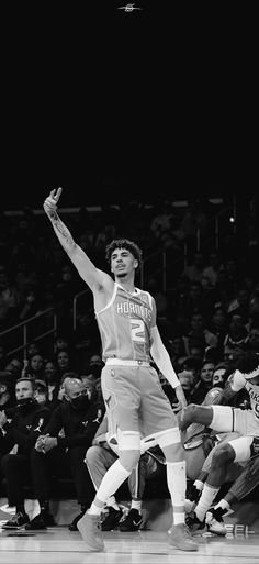 a black and white photo of a basketball player on the court with his arms in the air