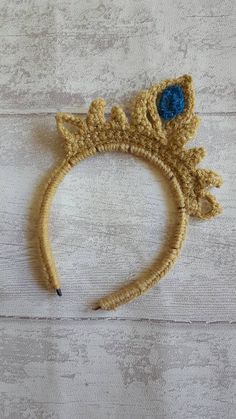 a crocheted headband with blue eyes and leaves on the side, sitting on a white surface