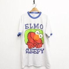 Vintage Elmo Sleepy T Shirt XL nose is fuzzy material Condition: cracking on graphic, stains front and back Tag reads: Heartland Apparel 100% cotton One Size Fits Most: estimated XL - check measurements in photos Made in USA **I like to recommend you compare the measurements listed to the measurements of a shirt you like the fit of to see if it will work** All measurements are taken with the garment flat on the ground. Convo with questions. Heartland, Festival Season, Favorite Outfit, Made In Usa, Gender Neutral, Bathing Beauties, Adult Outfits, Tops & Tees, Top Outfits