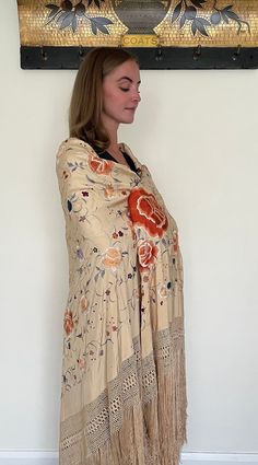 Here is a beautiful antique silk embroidered Manton de Manila shawl dating to the early part of the 20th century circa 1900 to 1910. The silk ground is in a rare buttermilk colour, I think that the listing photos which shows it worn by our model give a good indication of the actual colour. The richly coloured embroidery is in colours including orange, blue, lilac and white and it has long fringing and a hand knotted deep border to each side. The design includes large peony flowers and smaller fl Traditional Cream Silk Shawl, Embroidered Silk Shawl Scarf, Silk Floral Print Shawl, Cream Bohemian Pashmina Shawl For Wedding, Silk Pashmina Shawl For Wedding, Embroidered Silk Shawl, Bohemian Cream Dupatta With Traditional Drape, Beige Dupatta Scarf Shawl, Beige Shawl Dupatta