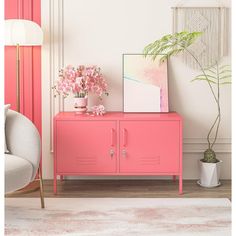 a pink cabinet sitting next to a white chair and potted plant on top of it