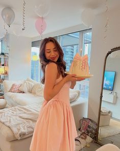 a woman in a pink dress holding a cake