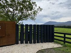 a wooden fence with metal posts in front of a grassy field