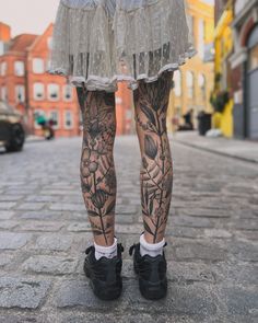 a woman's legs with tattoos on them and flowers in the middle of her leg