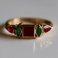 A garnet center is flanked by contrasting emerald and delicate blossoms of rubies. Unforgettable charm. 14k Gold Multi-stone Emerald Ring Gift, 14k Gold Multi-stone Emerald Ring As A Gift, Elegant Green Rings For Festive Occasions, Green Emerald Jewelry For Gift, Elegant Ruby Ring For Festive Occasions, Emerald Multi-stone Birthstone Ring Gift, Antique Ruby Multi-stone Jewelry, Emerald Cut Ruby Ring With Multi-stone, Multi-stone Emerald Ring As A Gift