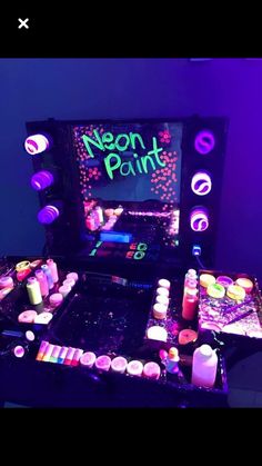 neon paint is on display in front of a television set with candles and other items