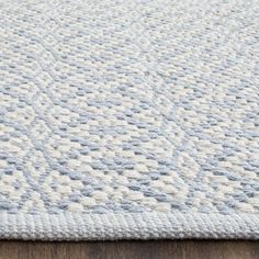 a white and blue rug on top of a wooden floor