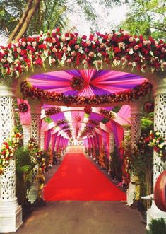 a red carpeted walkway with white pillars and flowers on the sides is decorated in pink