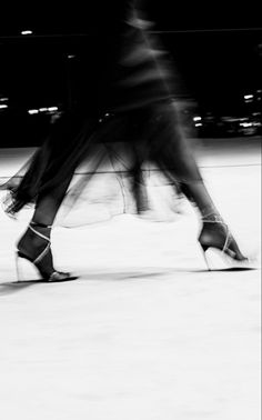 black and white photograph of two people walking down the street in high heeled shoes