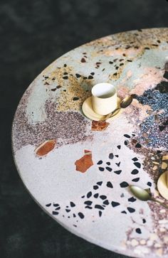 two candles are sitting on top of a table with paint splattered on it