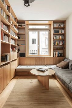 a living room with bookshelves, couch and coffee table in front of the window