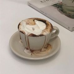 a white plate topped with a cup of hot chocolate and whipped cream on top of it