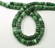 two strands of green glass beads on a white surface