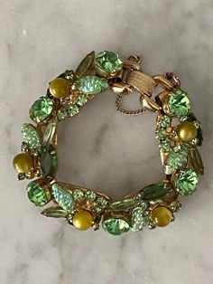 "This is a verified DeLizza & Elster Juliana bracelet. It can be seen in Ann Pitman's Juliana jewelry reference book and it's sought after and rarely seen. It was first seen in 1962. Verified on the isitjuliana website where one can find the companion brooch. Mr DeLizza referred to it as \"corn kernel\" or molded navette. It's dimensional and complete with olivine baubles, open back navettes, marquise and chatons. Put it altogether and you have this wonderful designer bracelet. The bracelet is 7 Retro Green Bracelet Jewelry, Vintage Green Evening Jewelry, Vintage Green Bracelets For Party, Vintage Green Bracelet For Anniversary, Vintage Green Jeweled Jewelry, Vintage Green Jubilee Bracelet, Retro Jeweled Bracelets For Formal Occasions, Retro Jeweled Bracelet For Formal Occasions, Vintage Oval Bracelets For Anniversary