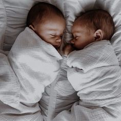 two babies are sleeping in blankets on top of each other