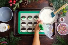 someone is decorating cookies with icing and sprinkles on a tray